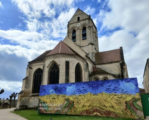De kerk Notre-Dame-de-l'Assomption in Auvers-sur-Oise met een reproductie van Van Goghs Korenveld met kraaien